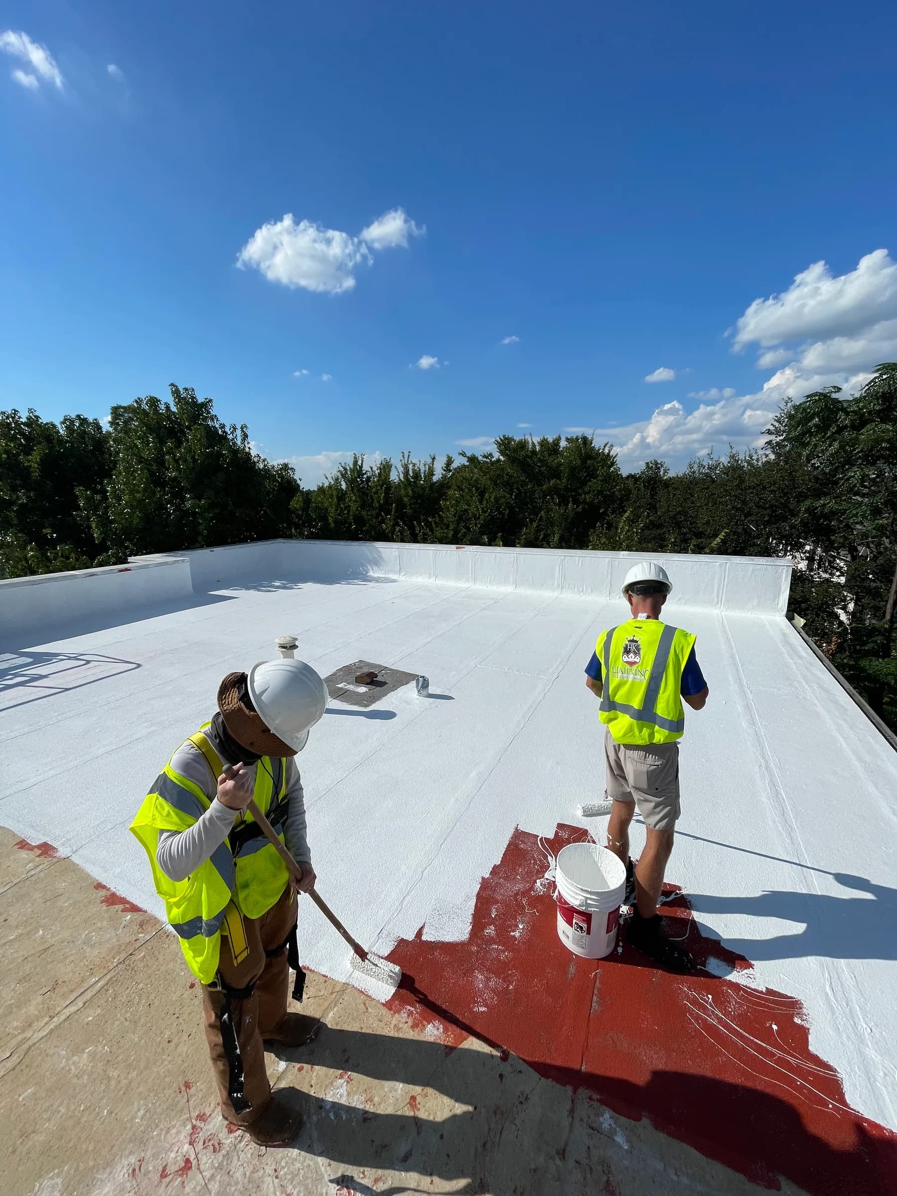 HailKing commercial roofing crew applying a white roof coating system