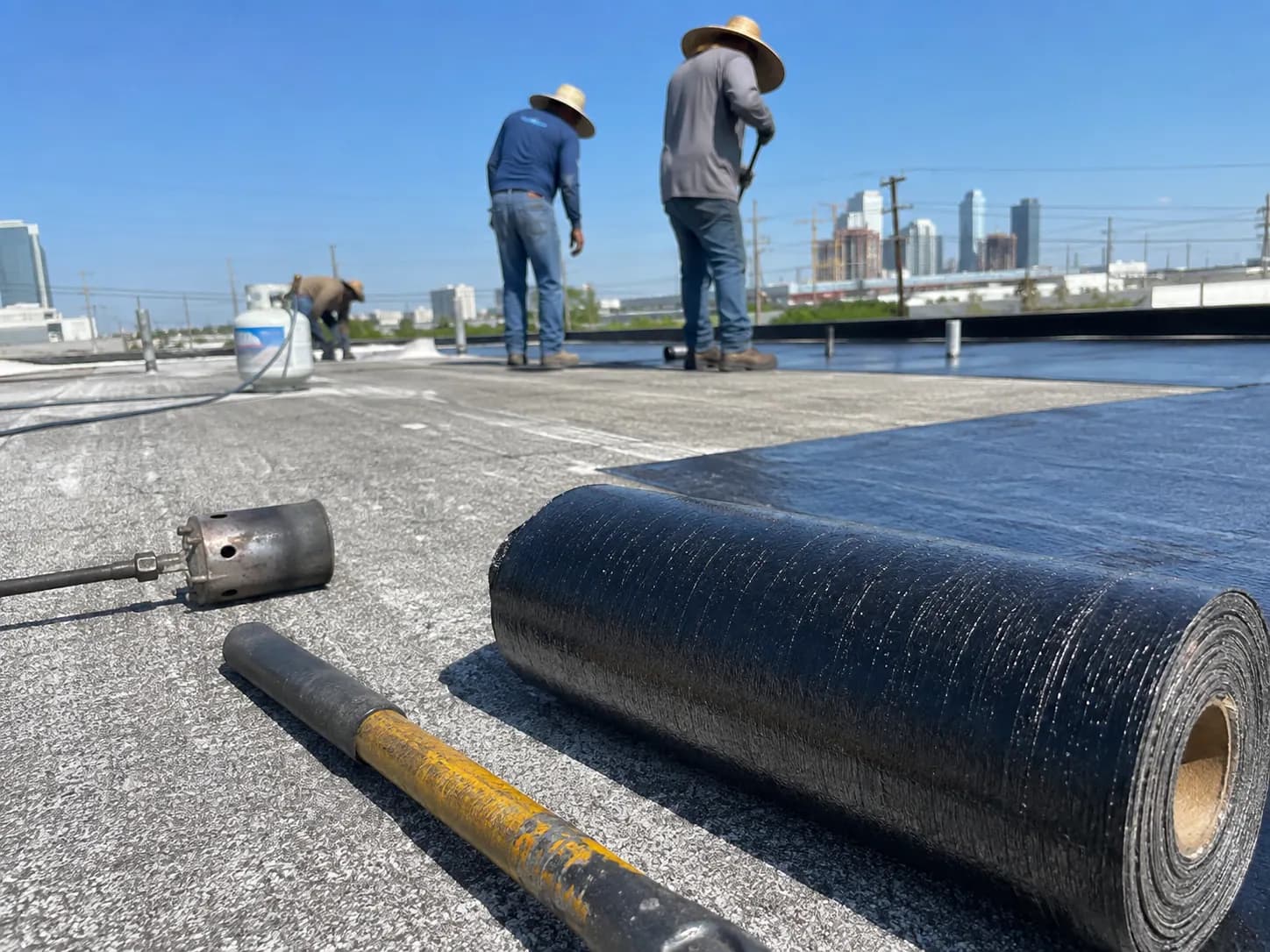Modified bitumen membrane roll beside an application torch on a commercial roof