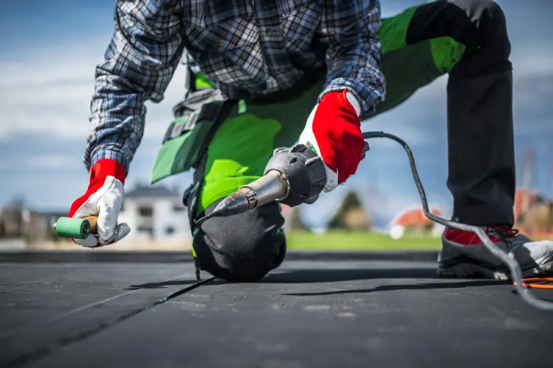 Commercial roofer sealing a black EPDM membrane detail