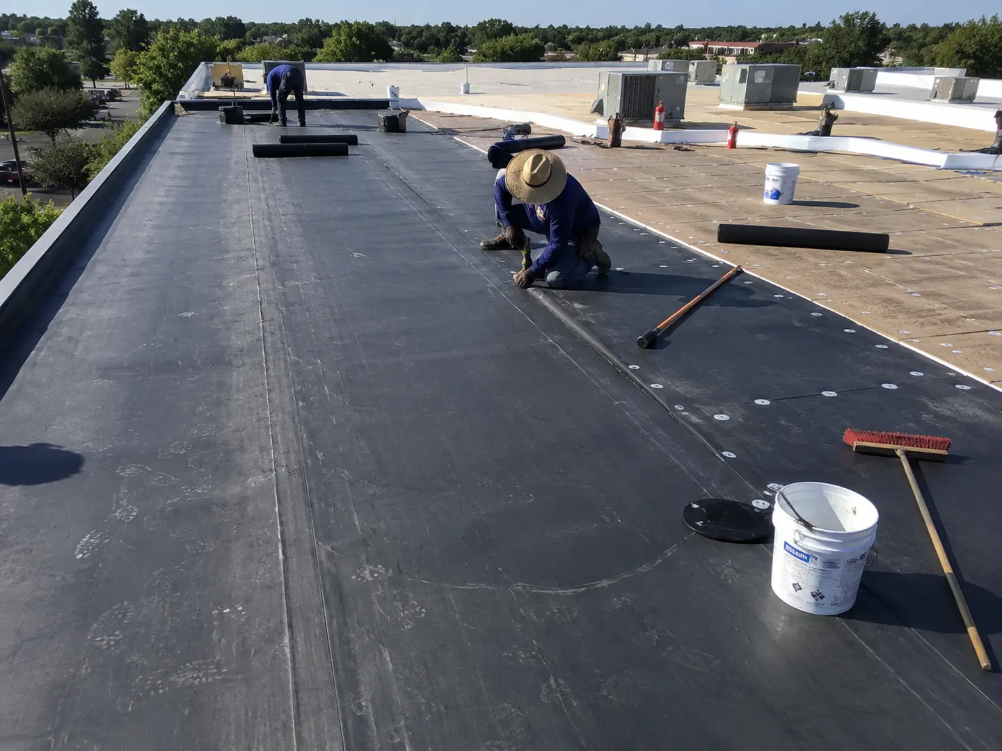 Commercial roofing crew placing black membrane over prepared insulation