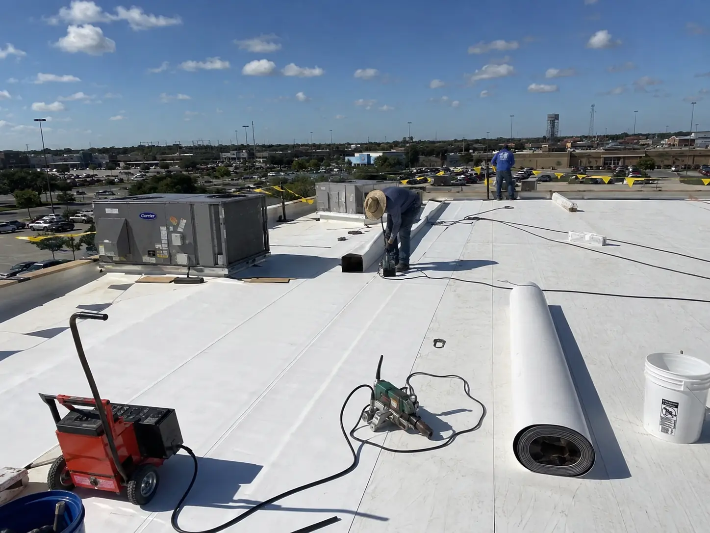 White commercial membrane roof installation around HVAC equipment