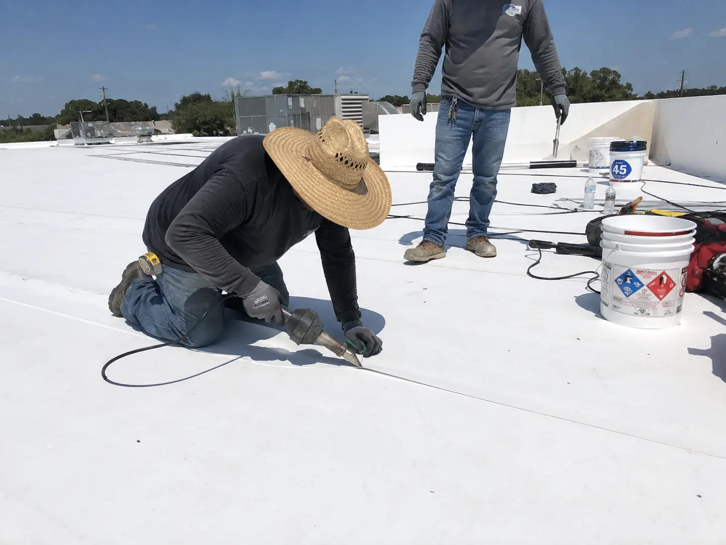 Commercial roofer hand-welding a white membrane seam