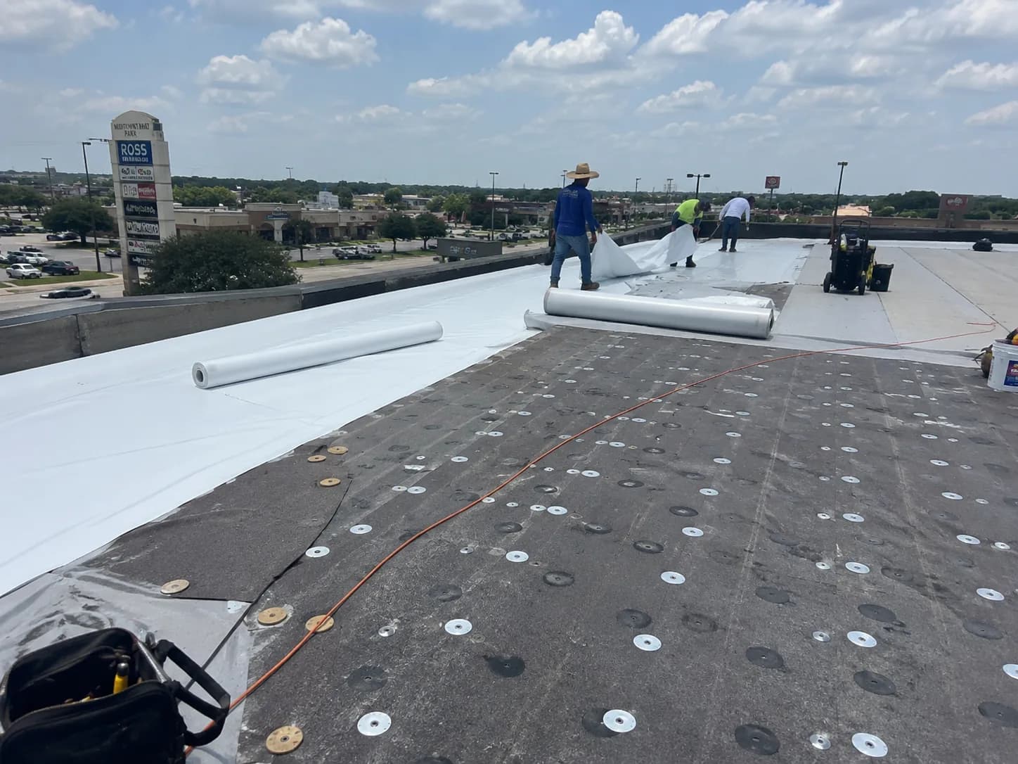 Hail King crew rolling white TPO membrane across a Dallas commercial roof
