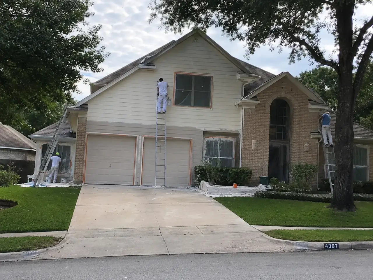 Painting crew working across the exterior of a two-story home