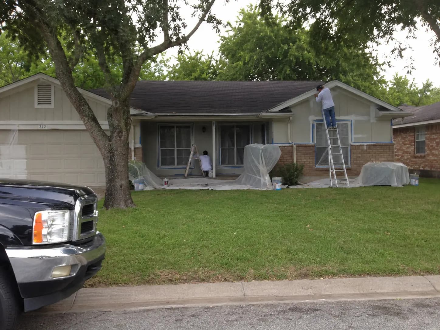 Exterior painting crew masking windows and preparing house siding