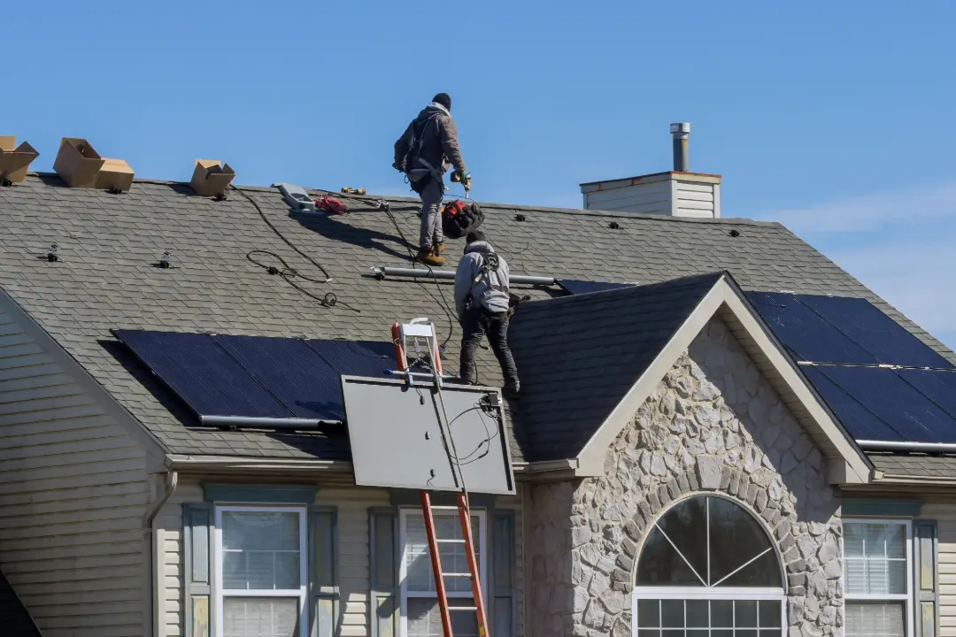 Solar installation crew positioning panels on a residential shingle roof