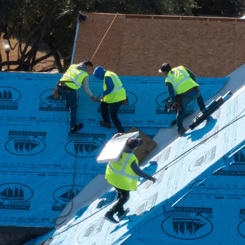 Crew installing synthetic underlayment on a roof