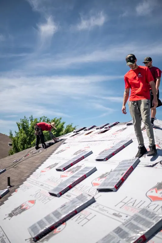 Roofing team installing underlayment on a pitched roof