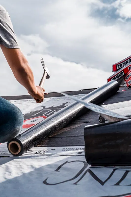 Installer preparing roofing material on a roof deck