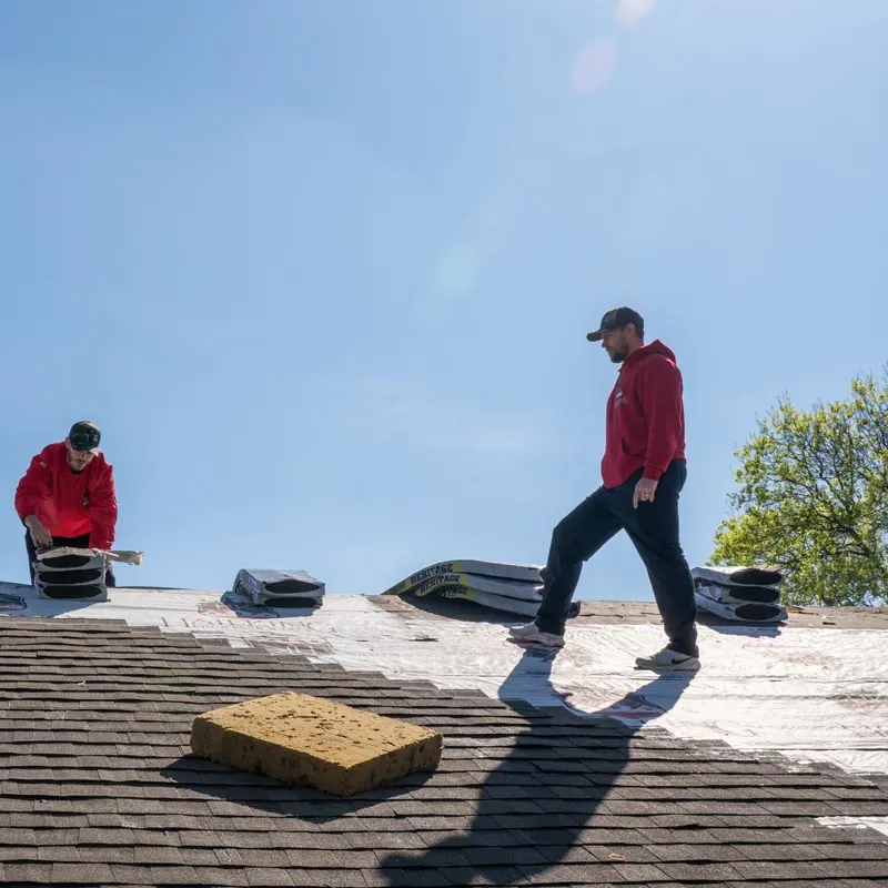 Installer carrying shingles across a roof deck