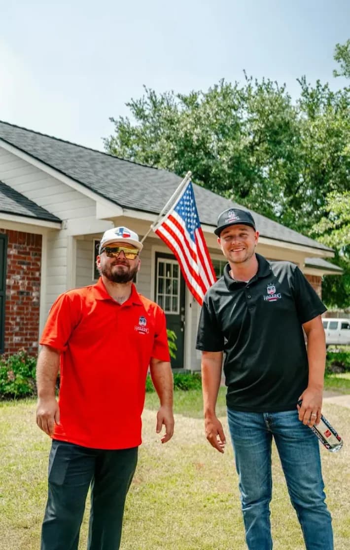 Two Hail King team members standing outside a home