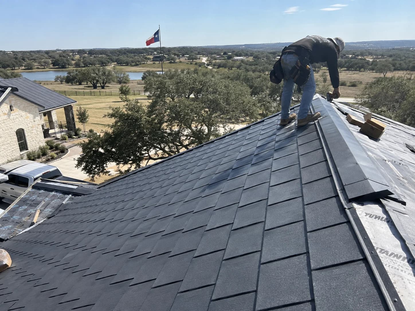 Roofer working along the ridge with metal roofing visible on an adjoining roof