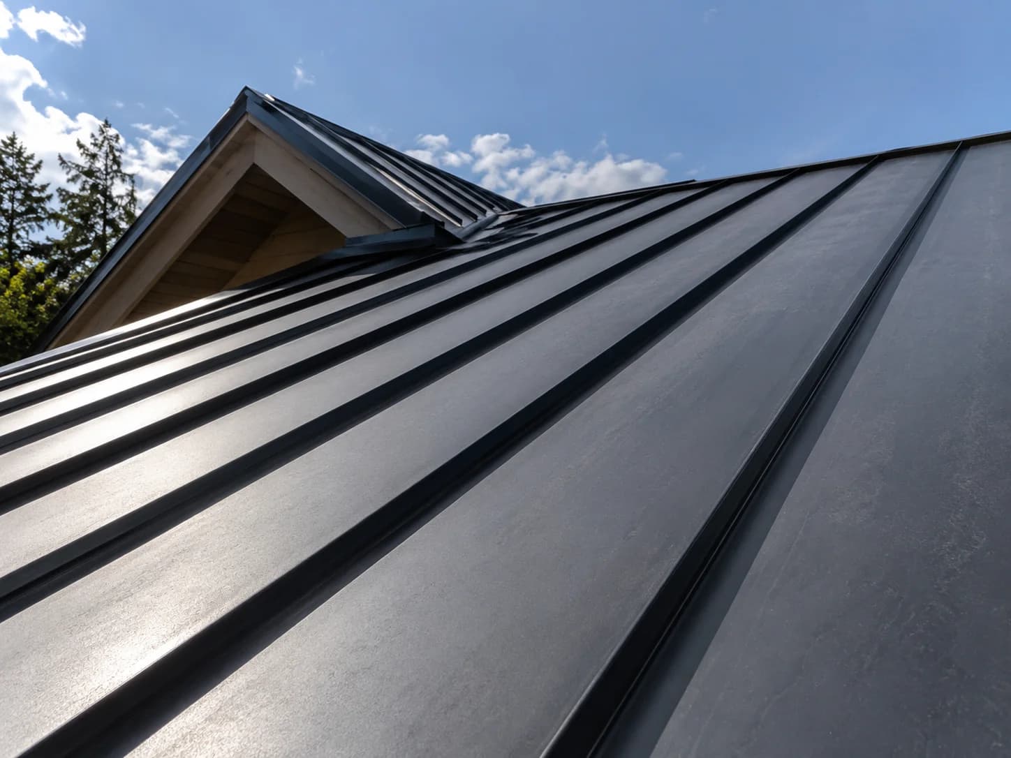 Close view of a dark standing seam metal roof around a gabled dormer