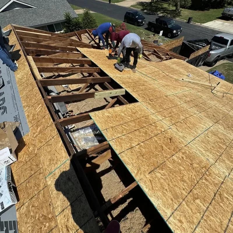 Roofing crew fitting new wood decking over exposed rafters