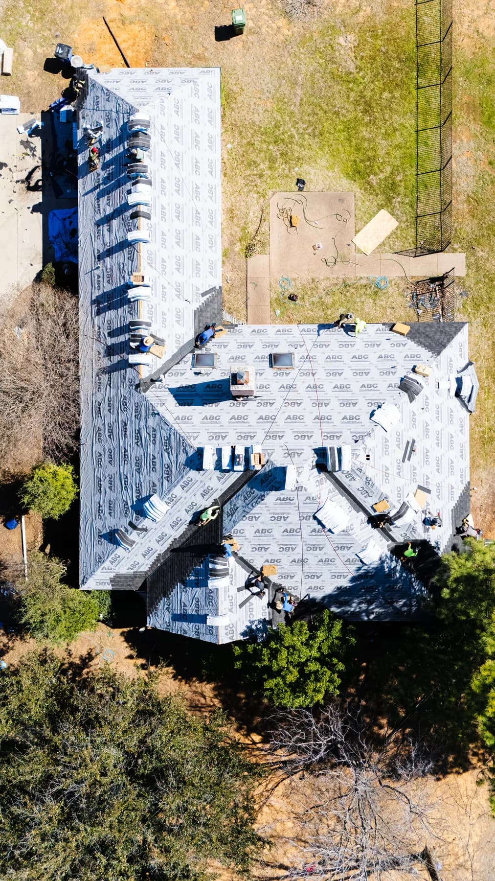 Overhead view of roofing crew installing shingles over underlayment