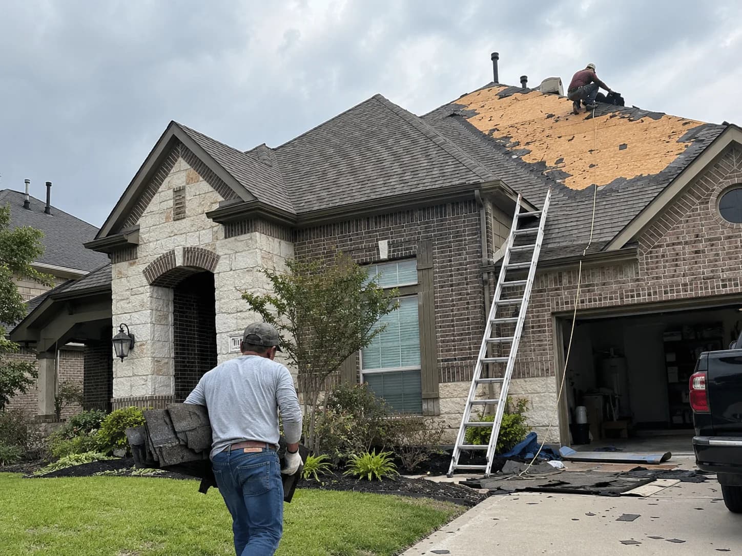 Roofers working on a home with shingles removed from part of the roof