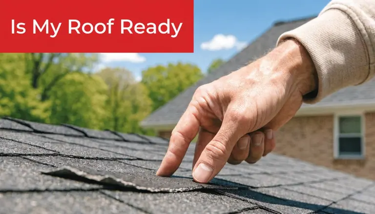 A close-up view of a person's hand inspecting a damaged asphalt shingle on a residential roof.