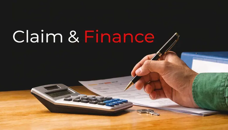 A person writing on financial documents with a calculator and keys on a wooden office desk.