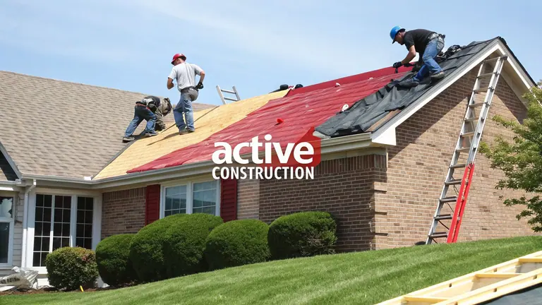 Roofers actively replace shingles and repair a residential house roof under a clear blue sky.