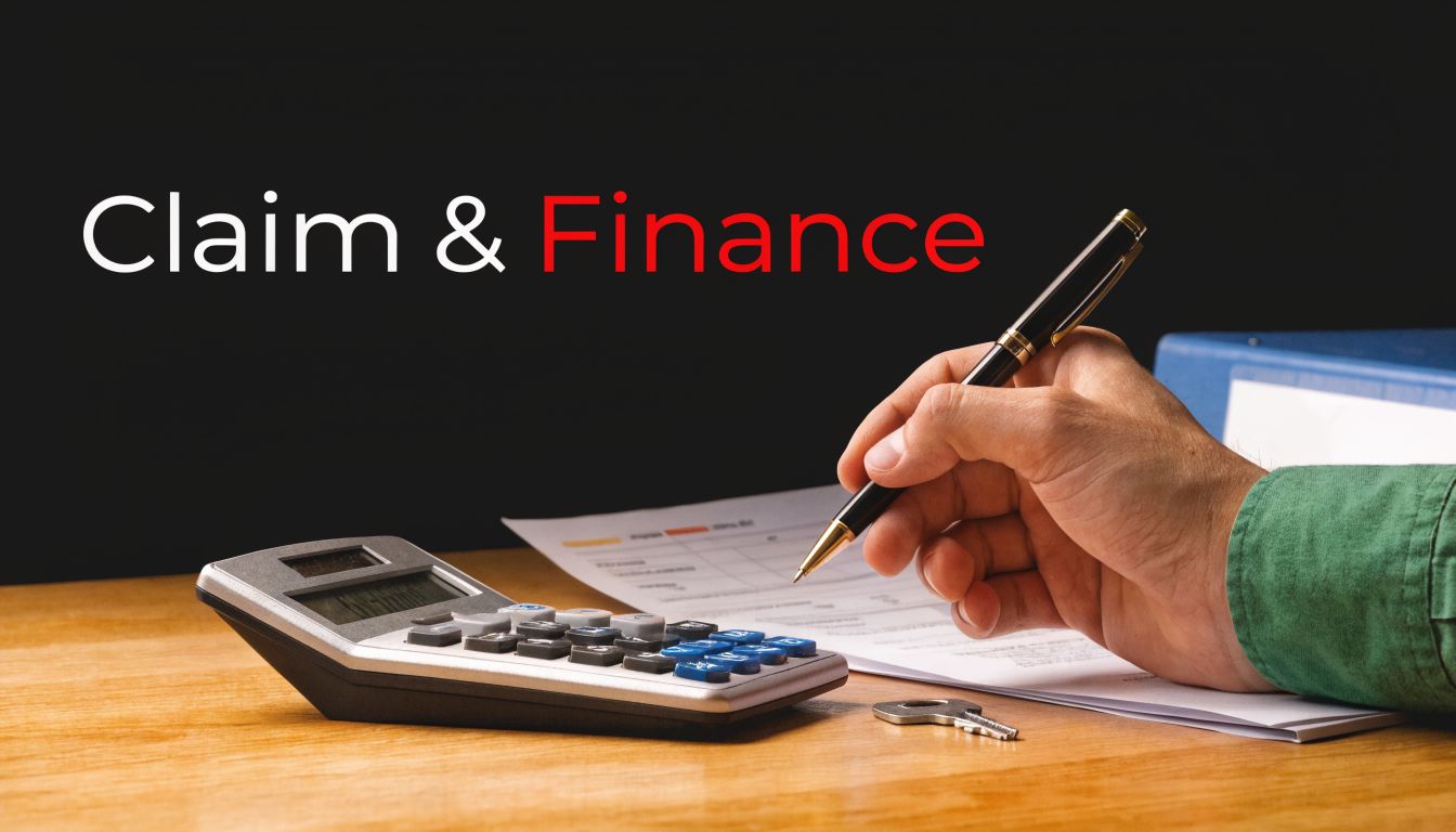 A person writing on financial documents with a calculator and keys on a wooden office desk.